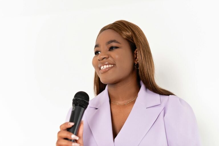 Smiling professional woman with microphone on white background, embodying leadership.